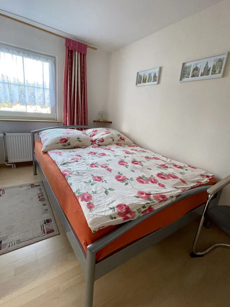 Schlafzimmer mit Doppelbett, hellem Fenster und Wernigerode-Bildern an der Wand